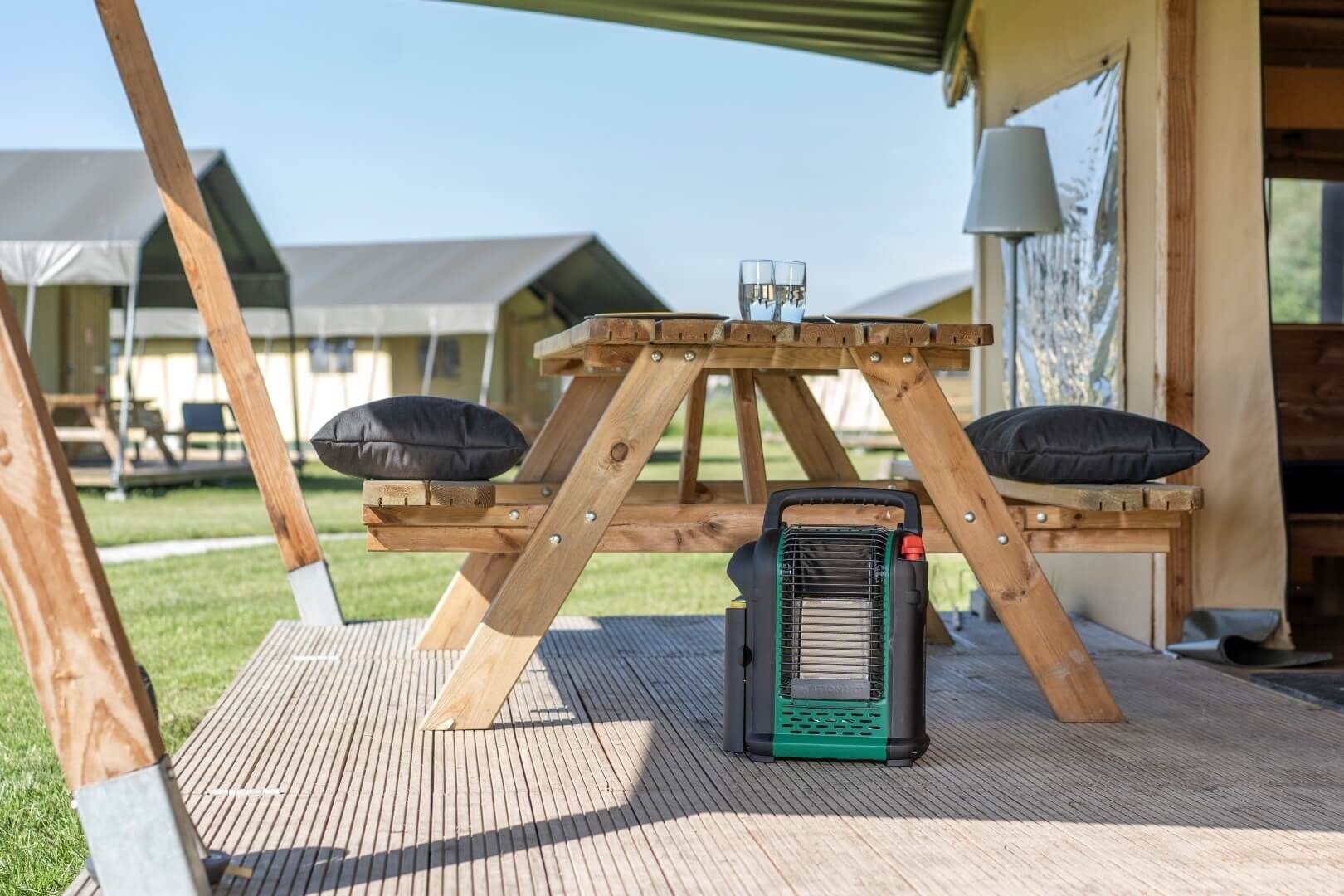Straalkachel op houten terras van een camping bij tent